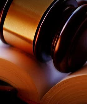 A wooden gavel resting on an open book with blank pages. - Olive Oil Times