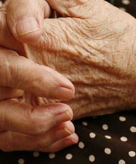 Close-up of elderly hands resting on a polka dot fabric surface. - Olive Oil Times