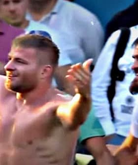 A shirtless wrestler celebrating with a crowd of spectators after a match. - Olive Oil Times