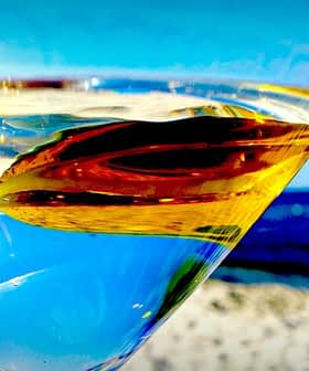 Close-up of a martini glass filled with clear liquid and an olive, with a blurred background. - Olive Oil Times