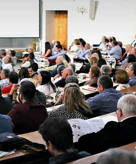 A large audience seated in a lecture hall during a conference presentation. - Olive Oil Times
