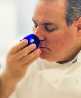 Chef smelling a blue cup during an olive oil tasting session in a professional kitchen. - Olive Oil Times