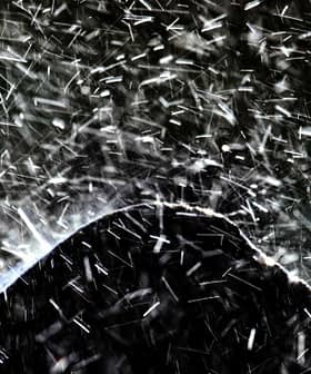 Close-up of water splashing in an abstract wave pattern against a dark background. - Olive Oil Times