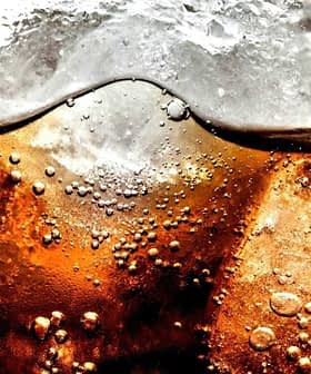 Close-up image of a carbonated beverage with ice cubes and bubbles visible in the liquid. - Olive Oil Times
