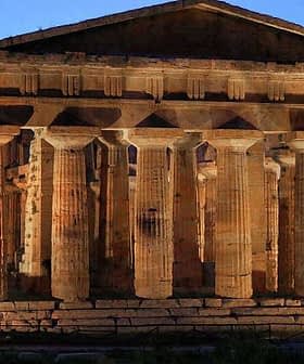 Ancient Greek temple structure with tall columns illuminated at dusk in Paestum, Italy. - Olive Oil Times