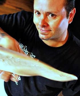 A pizza chef tossing a round piece of dough in a kitchen setting. - Olive Oil Times