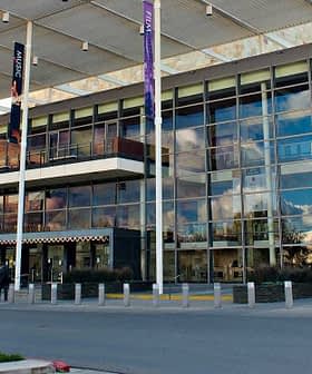 A modern commercial building featuring a glass facade and multiple banners. - Olive Oil Times