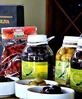 Bottles of olive oil, olives, and other products from Olivicola Simone displayed on a table. - Olive Oil Times