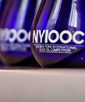 Blue glass awards with 'NYIOOC The New York International Olive Oil Competition' text displayed in a row. - Olive Oil Times