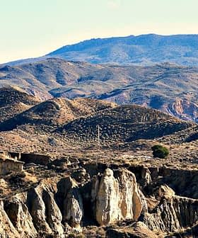 A panoramic view of a mountainous landscape featuring rolling hills and rocky terrain under a clear blue sky. - Olive Oil Times