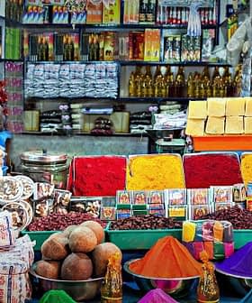 A variety of colorful spices, snacks, and packaged goods arranged in a market setting. - Olive Oil Times