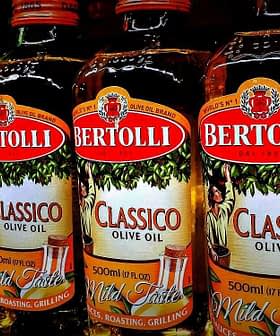 Row of Bertolli olive oil bottles in various types including Classico and Extra Light. - Olive Oil Times
