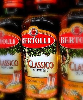 Bottles of Bertolli Classico and Extra Light olive oil lined up on a shelf. - Olive Oil Times