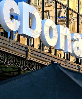 Signage of a McDonald's restaurant with reflective glass facade in the background. - Olive Oil Times
