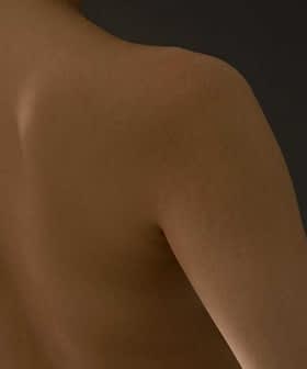 Close-up view of a bare back showing smooth skin and shoulder contours against a dark background. - Olive Oil Times