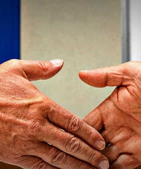 Two hands shaking in front of the European Union and Japan flags. - Olive Oil Times