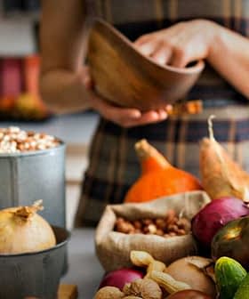 A variety of fresh vegetables and herbs displayed on a kitchen counter, including basil, onions, and peppers. - Olive Oil Times