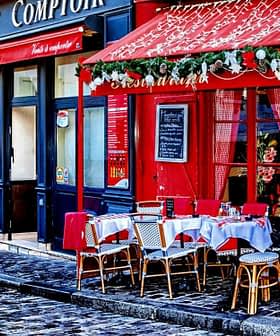 Outdoor café seating with tables and chairs arranged on a cobblestone street in Paris. - Olive Oil Times