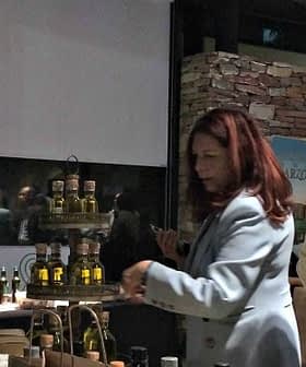 Group of individuals participating in an olive oil tasting event with various bottles displayed. - Olive Oil Times