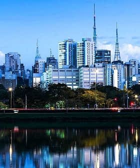 Cityscape of Sao Paulo featuring skyscrapers and reflections in water during dusk. - Olive Oil Times