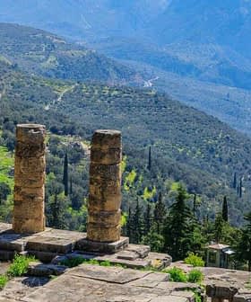 Stone columns of the ancient ruins at Delphi overlooking a mountainous landscape. - Olive Oil Times