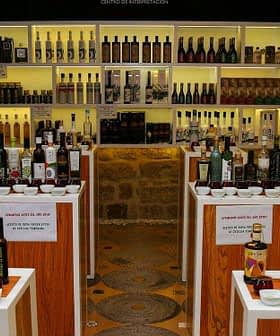 Interior view of an olive oil museum showcasing various bottles and products on display shelves. - Olive Oil Times