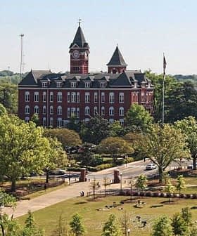 Aerial view of a university campus featuring a historic red brick building and green spaces. - Olive Oil Times