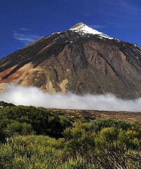 Mount Teide, a prominent volcano in Tenerife, with a snow-capped peak and surrounding clouds. - Olive Oil Times
