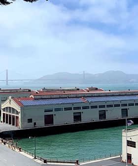 Historic waterfront buildings near the Golden Gate Bridge with water in the foreground and hills in the background. - Olive Oil Times