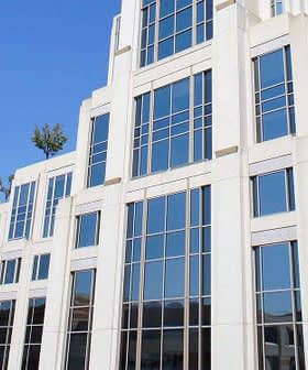 A modern building with a glass facade and geometric design, featuring multiple windows and a pointed top. - Olive Oil Times