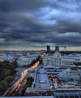 A panoramic view of Madrid's skyline during dusk with cloudy skies and city lights. - Olive Oil Times