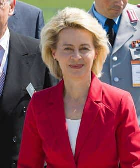 A group of officials, including a woman in a red suit, walking together at an outdoor event. - Olive Oil Times