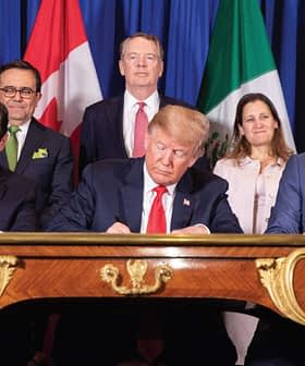 Political leaders signing the USMCA agreement at a table with flags of the US, Canada, and Mexico in the background. - Olive Oil Times