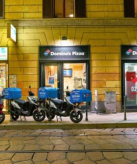 Row of delivery motorcycles parked outside a Domino's Pizza location at night. - Olive Oil Times