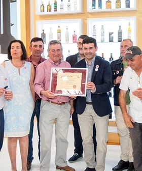 A group of individuals standing together, holding an award certificate in a well-lit indoor setting. - Olive Oil Times