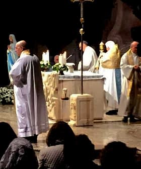 Clergy members conducting a religious ceremony at an altar with candles and decorations. - Olive Oil Times