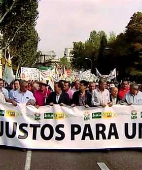 Group of people marching in a protest holding a large banner that reads 'Precios Justos Para Un Olivar'. - Olive Oil Times