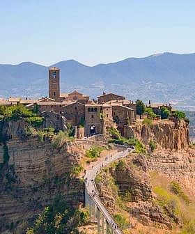 Aerial view of Civita di Bagnoregio, an ancient hilltop village in Italy, surrounded by mountains and valleys. - Olive Oil Times