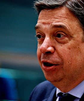 A man in a dark suit speaking during a formal event or meeting. - Olive Oil Times