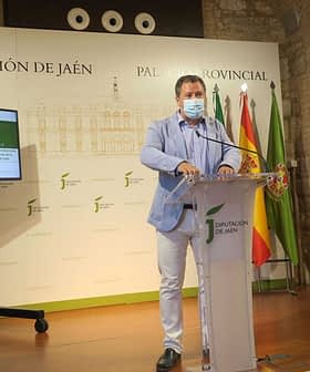 Man speaking at a podium during a press conference at Diputación de Jaén with a screen in the background. - Olive Oil Times