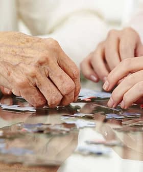 Two hands working together to assemble pieces of a jigsaw puzzle on a table. - Olive Oil Times