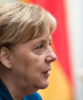 Profile view of Angela Merkel with short hair and a blue jacket, set against a blurred background. - Olive Oil Times