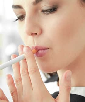 A woman with long hair lighting a cigarette with a lighter in her hand. - Olive Oil Times