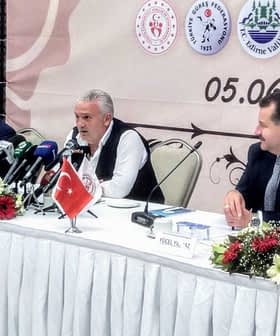 Group of officials seated at a table during a press conference with microphones and a Turkish flag. - Olive Oil Times