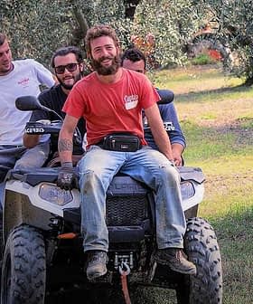 Four men riding on an all-terrain vehicle in an olive grove. - Olive Oil Times