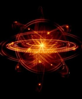 Abstract illustration of an atom with glowing rings and a central nucleus on a black background. - Olive Oil Times