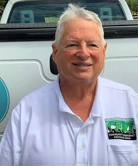 Man wearing a white shirt with a Community Emergency Response Team badge standing by a truck. - Olive Oil Times