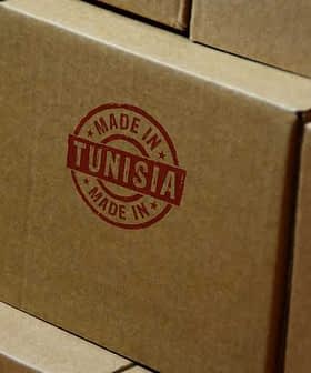 Stack of cardboard boxes featuring a red 'Made in Tunisia' stamp on the side. - Olive Oil Times