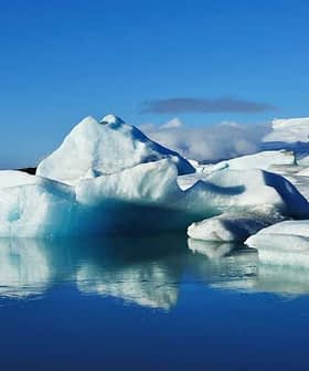 Icebergs of various shapes and sizes floating in calm water under a clear blue sky. - Olive Oil Times