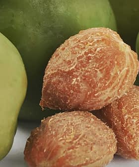 Several green apples with a cluster of olive pits in the foreground. - Olive Oil Times